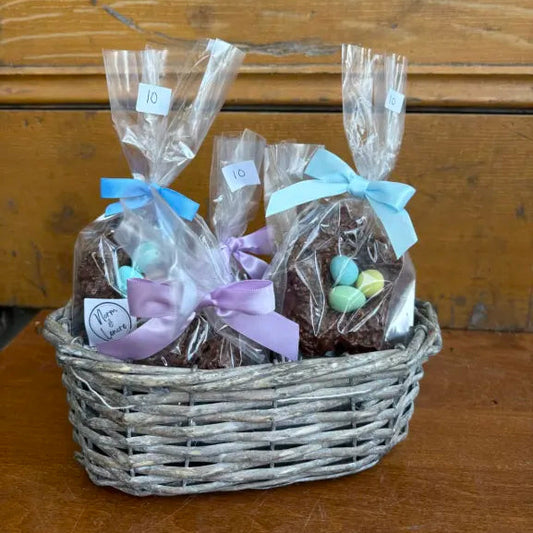 Basket of brownies in clear cellophane with decorative ribbons on a wooden surface